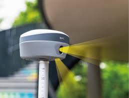Scanner 3D topographique gris sur perche, projetant des faisceaux lumineux jaunes pour la collecte de données.